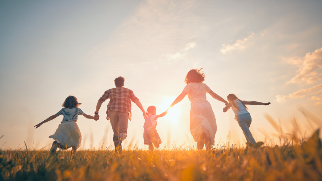 A family is running in a meadow at sunset. plan holiday season with rich ranch