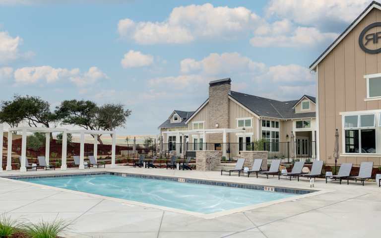 A swimming pool and lounge chairs in front of a house in meadow view townhomes rice ranch